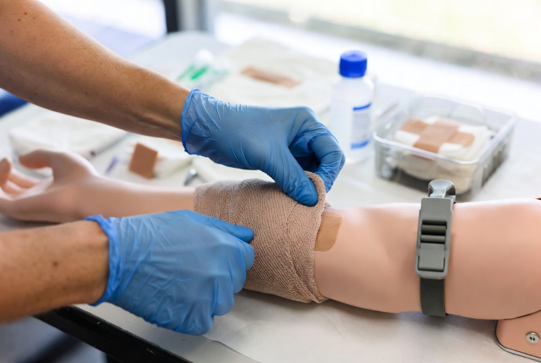 Verbandtraining an einer Übungspuppe mit Handschuhen